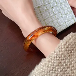 Close-up of elegant amber irregular resin bangle showing transparent texture on wrist