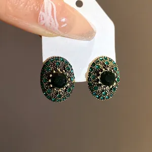 Vintage green crystal oval stud earrings featuring an antique gold frame and silver needles
