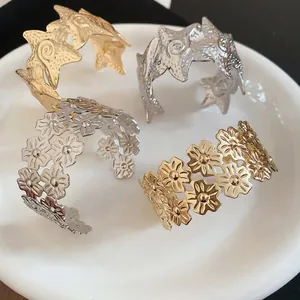 Close-up of gold and silver star and daisy flower cuff bracelets on a white plate