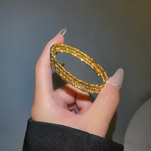 Dettaglio ravvicinato di un elegante bracciale dorato multistrato con perle metalliche