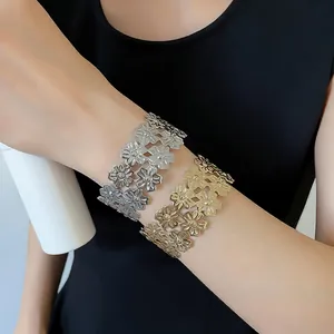 Detailed view of textured metal flower cuff bracelets on arm in gold and silver finish.