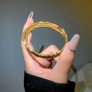 Primo piano di un bracciale dorato multistrato con perle metalliche testurizzate.