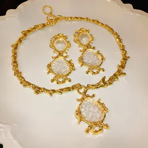 Detailansicht eines vergoldeten Vintage-Schmucksets auf einem weißen Keramikteller.