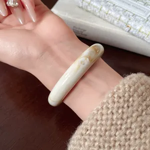 Close-up of irregular cream marble resin bracelet on wrist with minimalist aesthetic