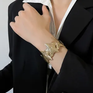 Gold pleated star cuff bracelet worn with a black blazer for a chic luxury style.