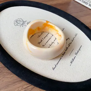 Detailed shot of an irregular resin bangle featuring orange and cream marble texture
