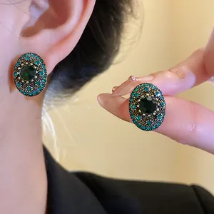 Detail of vintage oval stud earrings with emerald green crystals and gold setting