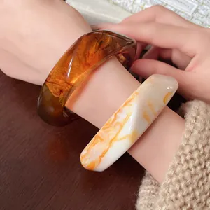 Close-up of irregular resin bracelets with amber and marble texture on wrist