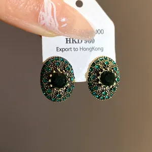Close-up of vintage oval green rhinestone earrings with silver needle base