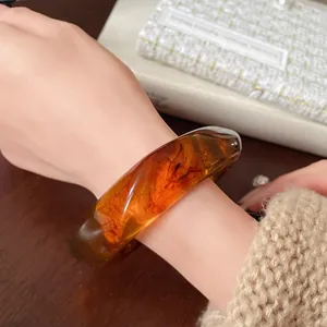 Elegant close-up view of a vintage amber irregular resin bangle worn on a model wrist