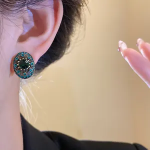 Elegant detailed close-up of a vintage oval earring with green stones worn by a model