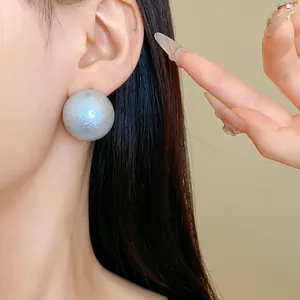 Close-up of a large iridescent cotton pearl stud earring on an Asian model's ear