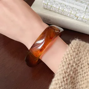 Close-up detail of a stylish vintage amber irregular resin bracelet on a female wrist