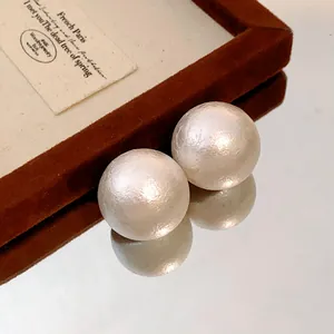 Close-up of cotton pearl stud earrings with a soft matte textured finish.