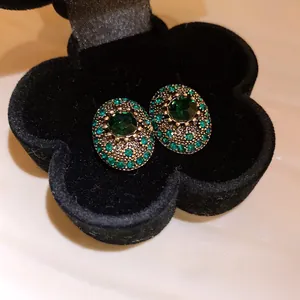 Detailed macro view of vintage oval stud earrings with emerald green crystals