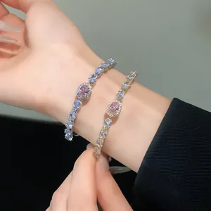 Close-up of elegant zircon oval open bracelets with pink and blue stones on wrist