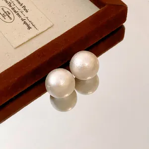 Macro detail shot of elegant vintage white cotton pearl stud earrings on a mirrored surface