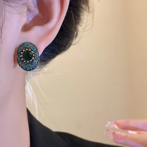 Detailed close-up of a vintage-style oval stud earring featuring vibrant green rhinestones