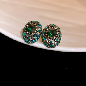 Detailed view of vintage oval earrings with green emerald stones in a retro gold setting
