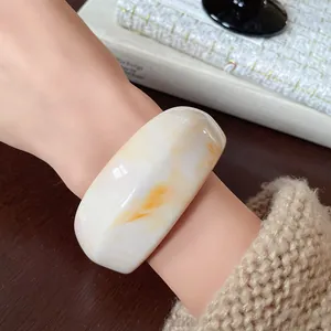 Detailed view of a minimalist irregular resin bangle with amber marbling on an arm.
