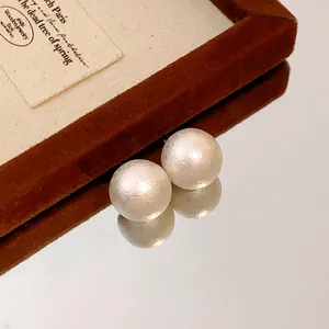 Detailed view of elegant matte textured cotton pearl stud earrings with vintage silver needles