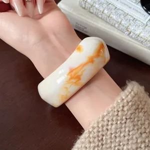 Macro detail of irregular white resin bangle with vibrant orange marble pattern