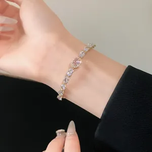 Close-up of elegant gold bracelet featuring pink and clear oval-cut cubic zirconia crystals