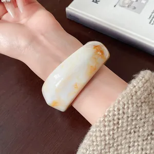Close-up of minimalist irregular resin bracelet with orange marble texture on wrist