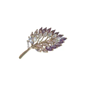 Elegant gold plated leaf brooch decorated with purple and clear marquise zircons