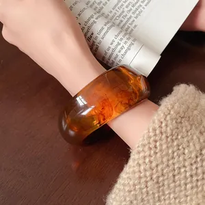 Close-up of amber irregular resin bangle with artistic swirl patterns on wrist