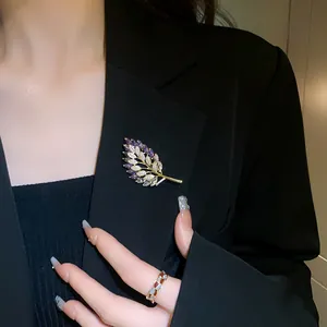 Elegant gold-plated leaf brooch with purple zircons pinned on a stylish black blazer.