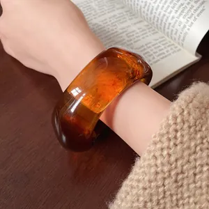 Close-up of translucent amber resin bangle on wrist with warm vintage background