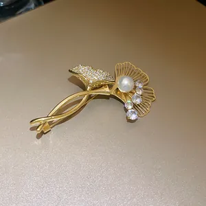 Detailed close-up view of a gold ginkgo leaf brooch with zircons and a white pearl accent