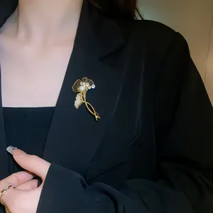 Elegant gold plated ginkgo leaf brooch with pearl and zircon detail on black blazer jacket