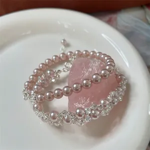 Nahaufnahme eines eleganten rosa Perlenarmbands mit Zirkon-Blumenweberei auf Kristall.