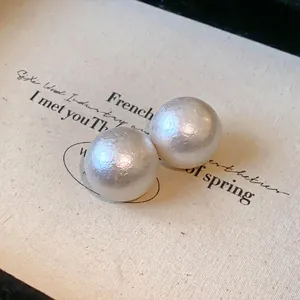 Detailed macro view showing the unique textured finish of white cotton pearl stud earrings.
