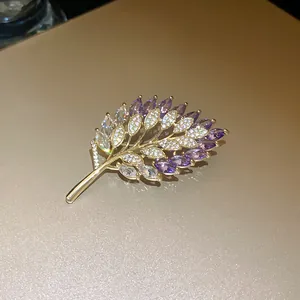 Elegant close-up detail of a leaf-shaped gold plated brooch with purple zircons