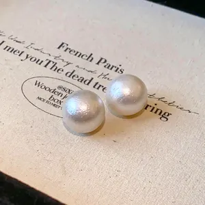Macro view of white cotton pearl stud earrings showing elegant vintage textured finish