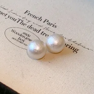 Close-up detail of elegant white cotton pearl stud earrings with vintage textured finish