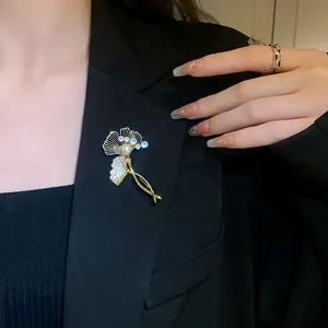 Elegant gold plated ginkgo leaf brooch with zircon and pearl detail on black blazer
