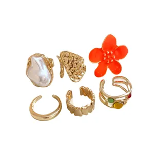 Gold-toned irregular geometric open ring set with enamel flower and faux pearl accents.