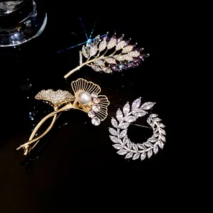 Close-up of three elegant gold-plated brooches with sparkling zircons and a pearl