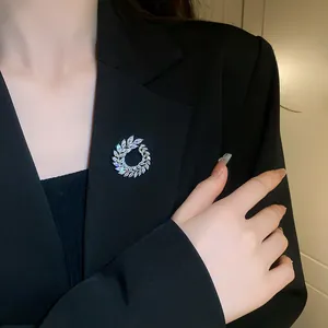 Close-up detail of a silver-tone wreath brooch with marquise-cut zircons on a blazer