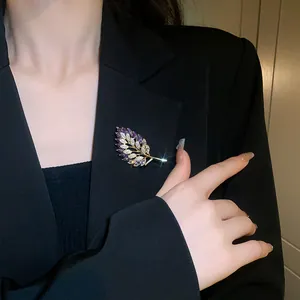 Elegant purple zirconia leaf brooch with gold plating shown pinned on a black blazer