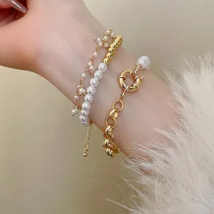 Élégants bracelets en perles dorées à plusieurs rangs avec fermoir TO portés au poignet