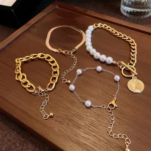 Ensemble de bracelets en chaîne dorée et perles avec pendentif pièce sur plateau bois