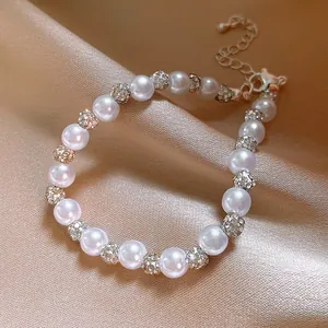 Zoom sur un bracelet en perles d'eau douce roses avec boules strass sur un fond de soie