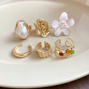 Macro view of a 6-piece gold-toned geometric irregular open ring set on a white plate