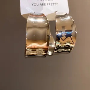 Close-up view of vintage style gold C-shaped hoop earrings with glossy finish
