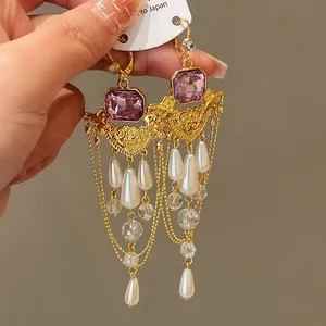 Détail macro de boucles d'oreilles vintage avec gemmes mauves, perles et glands cristal